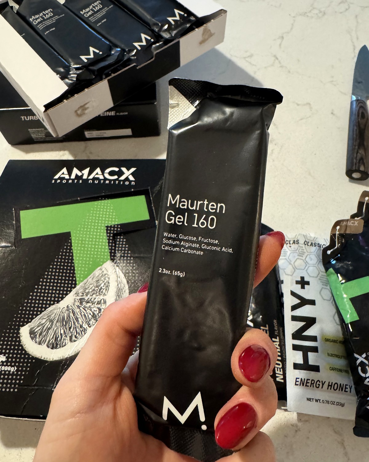 Maurten Gel 160 in hand with a box of Amacx Turbo Gels behind it