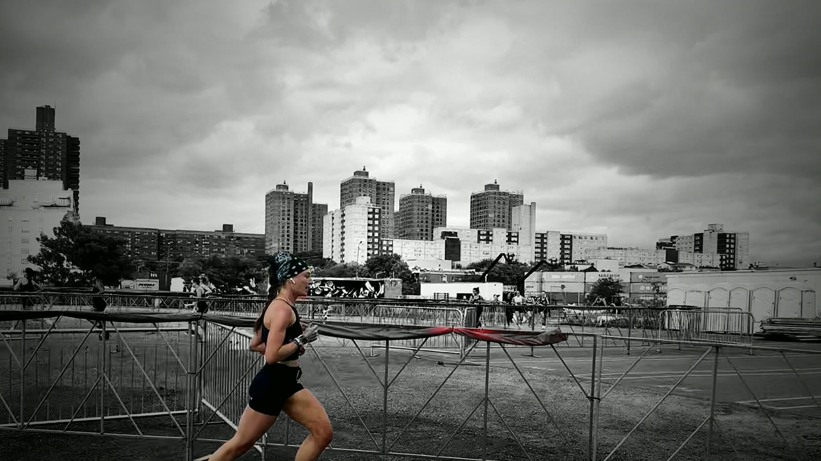 Brianna racing past orange barriers with the city skyline behind