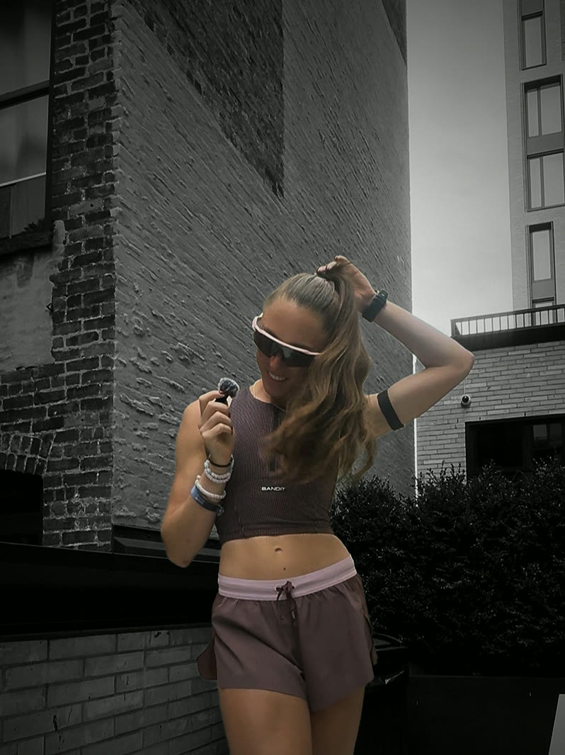 Checking a watch on a brick terrace in a mauve crop and shorts